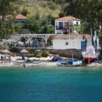 Hydra island beach with taverna and traditional coastal village Greece