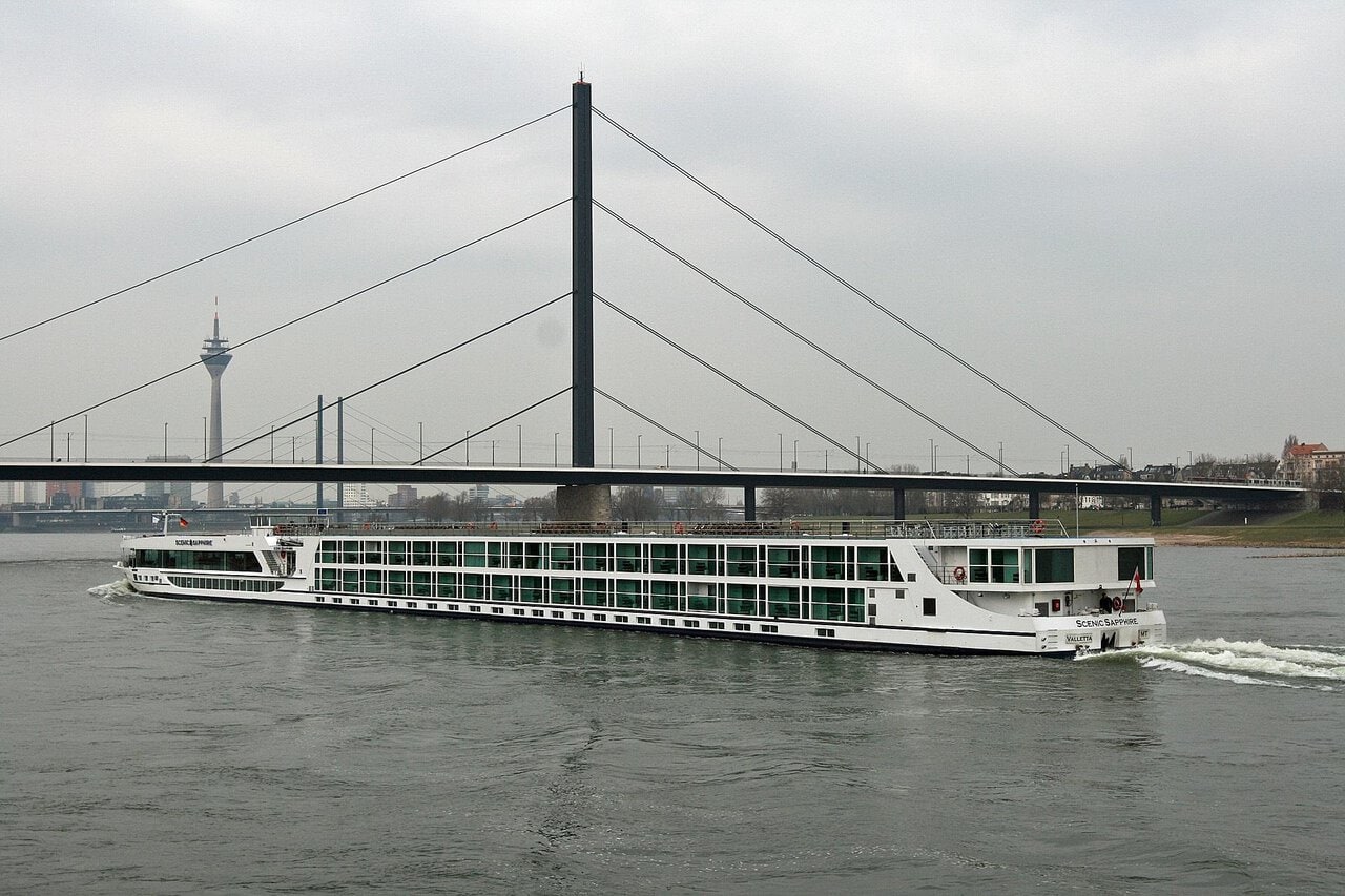 DĂĽsseldorf Rhine river cruise boat passing under bridge with city skyline