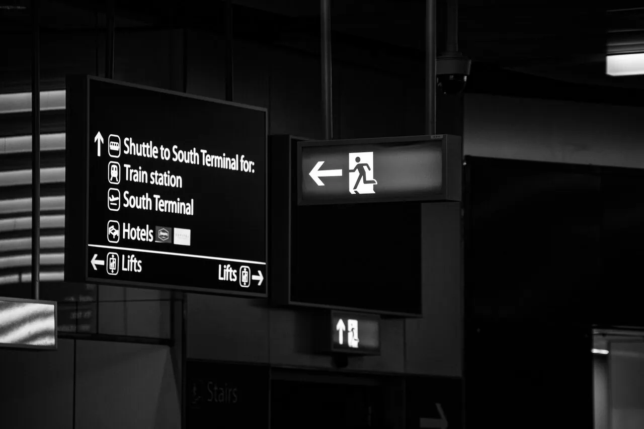 Signage inside Gatwick Airport terminal showing directions to train station and South Terminal