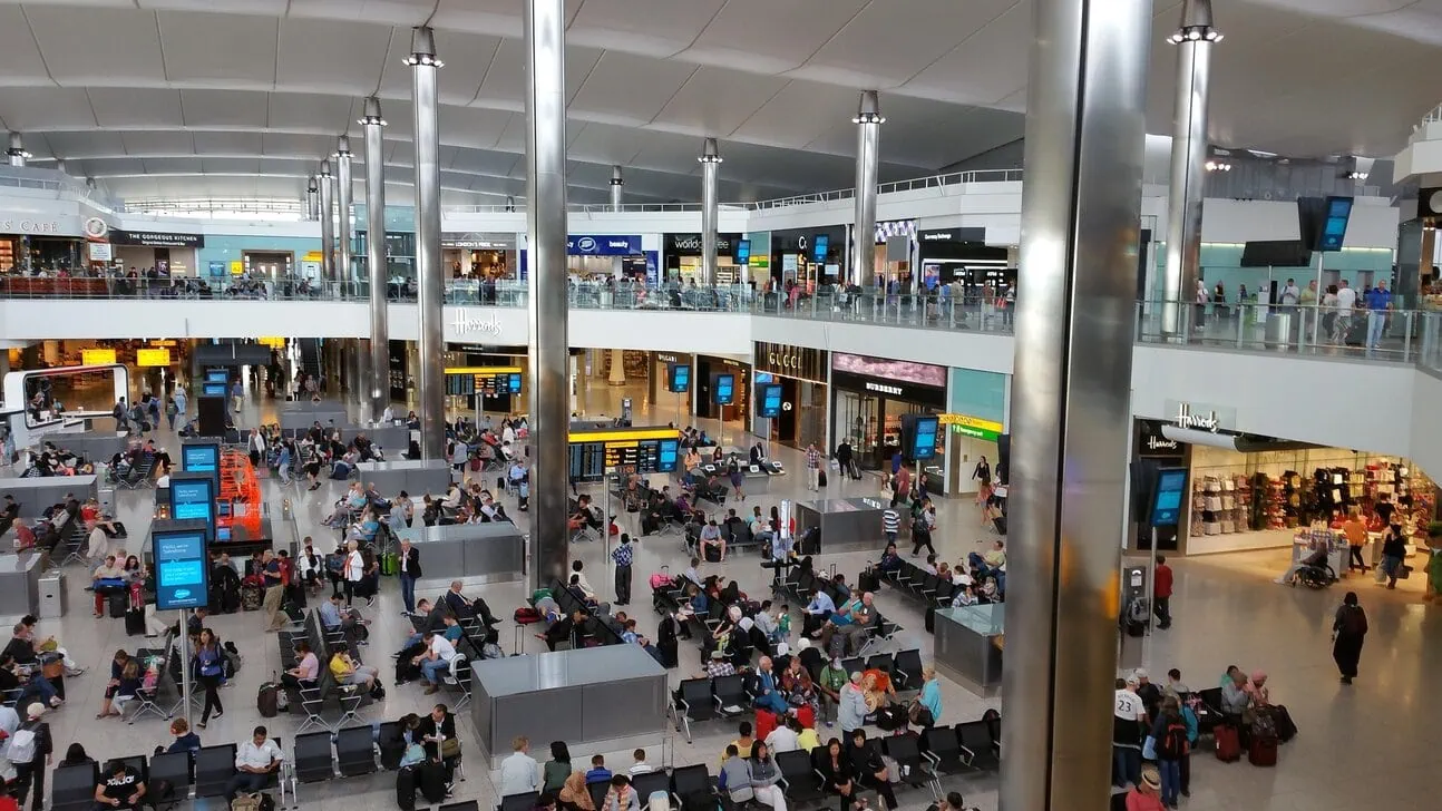 Passengers waiting inside Heathrow Airport terminal departure hall