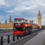Hop on hop off bus crossing Westminster Bridge with Big Ben and Houses of Parliament in London