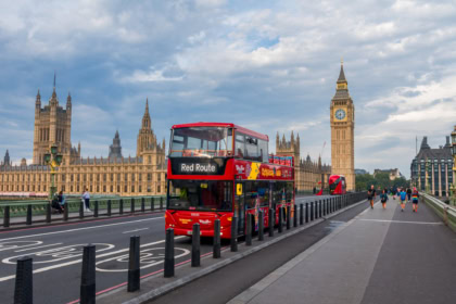 Hop on hop off bus crossing Westminster Bridge with Big Ben and Houses of Parliament in London