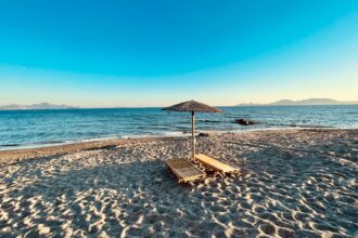 Kos beach with sunbeds and parasol overlooking the Aegean Sea in Greece