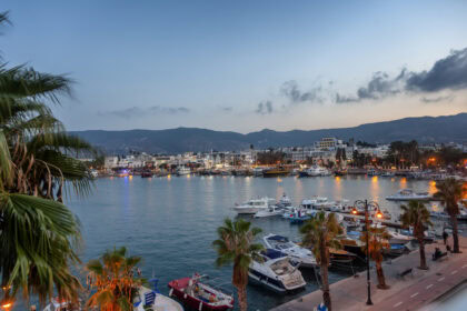 Kos Town harbour at sunset with boats, waterfront and palm trees in Greece