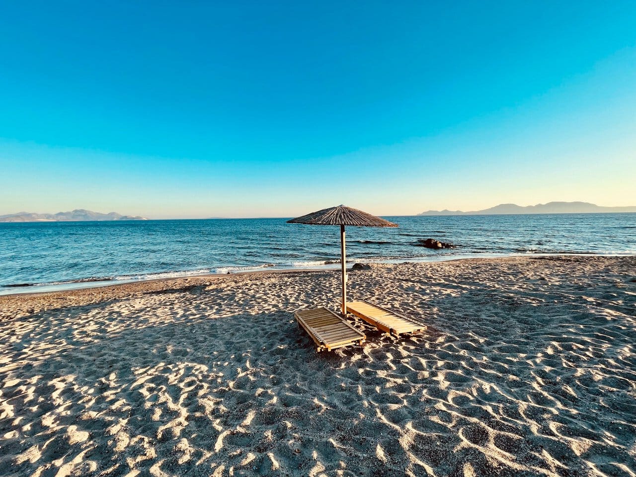 Kos beach with sunbeds and parasol overlooking the Aegean Sea in Greece