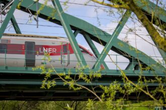 LNER train crossing a green steel bridge on the East Coast Main Line in the UK