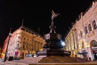 Eros statue at Piccadilly Circus London at night with illuminated buildings