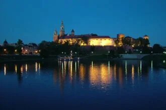 Wawel Castle at night reflected on the Vistula River in Krakรณw