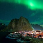 Northern Lights over fishing village and mountains in Lofoten Islands Norway