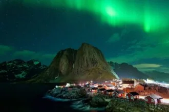 Northern Lights over fishing village and mountains in Lofoten Islands Norway