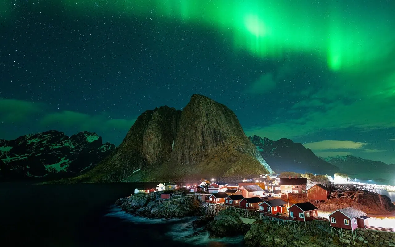 Northern Lights over fishing village and mountains in Lofoten Islands Norway