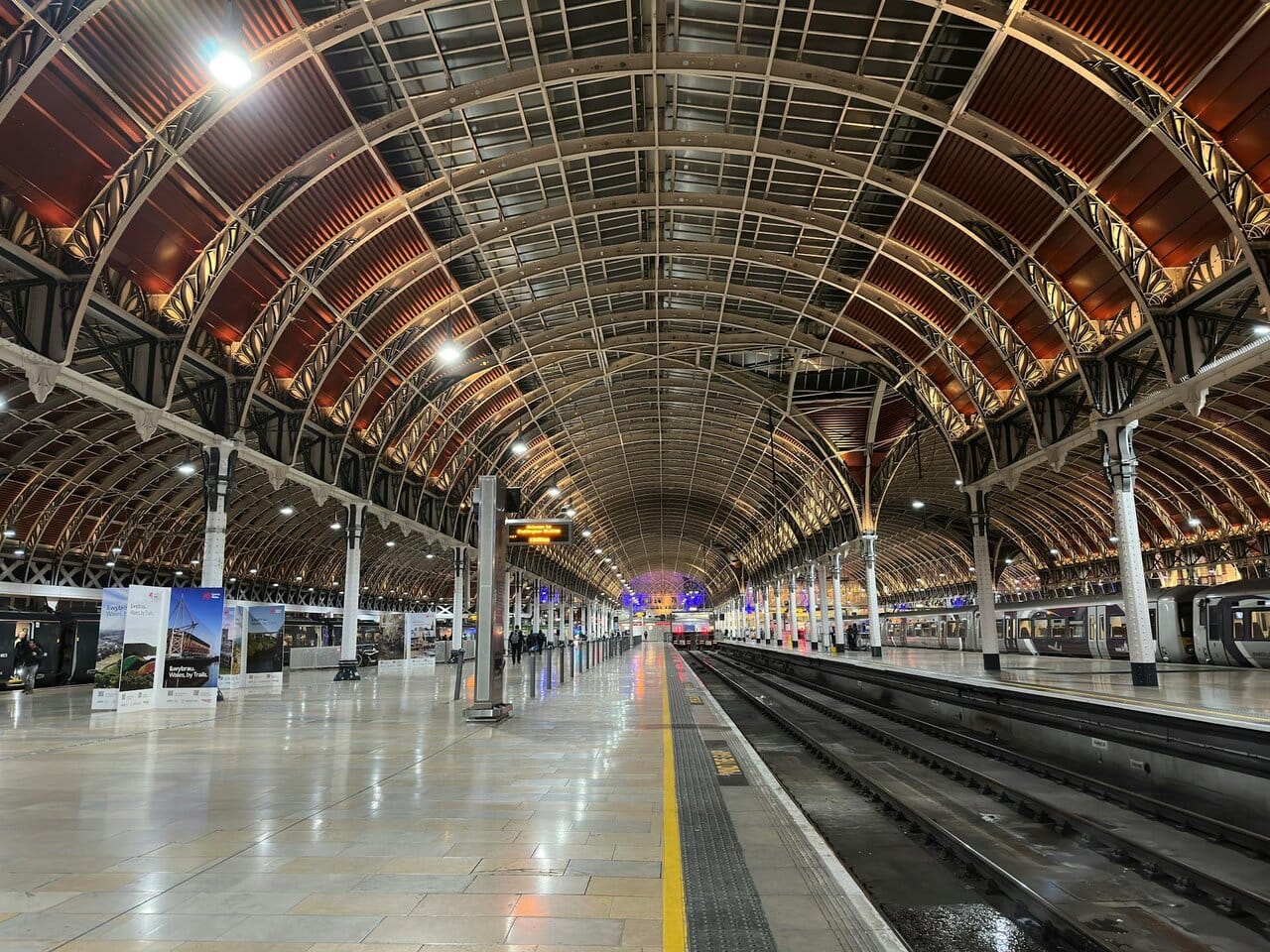 London Paddington train station platform with trains and Victorian roof structure