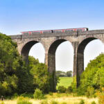 Train crossing stone railway viaduct in rural Wales countryside