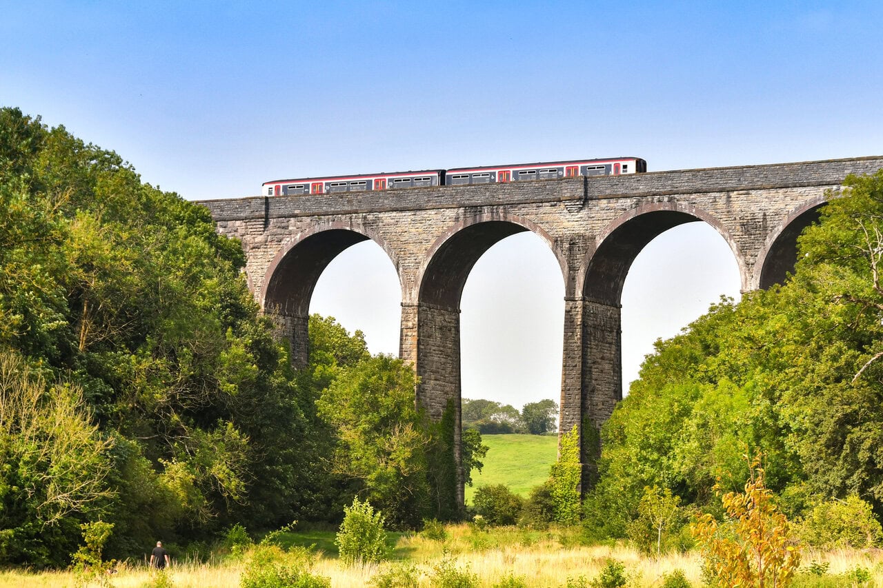 Train crossing stone railway viaduct in rural Wales countryside