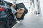 Traveller entering private airport transfer vehicle at terminal pickup zone