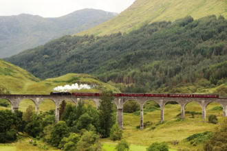 Steam train crossing Glenfinnan Viaduct on the West Highland Line in Scotland