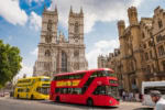 Westminster Abbey in London with red double decker buses on the street