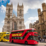 Westminster Abbey in London with red double decker buses on the street