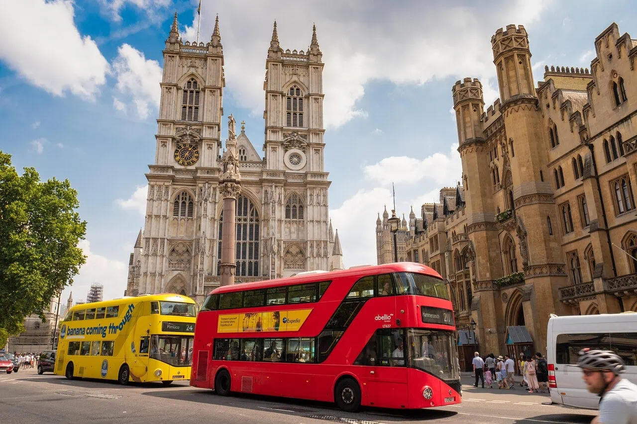 Westminster Abbey in London with red double decker buses on the street