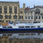 City Cruises boat on the River Ouse in York with historic buildings behind