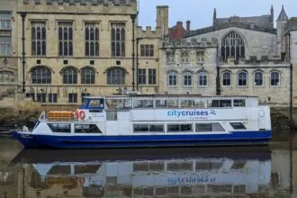 City Cruises boat on the River Ouse in York with historic buildings behind