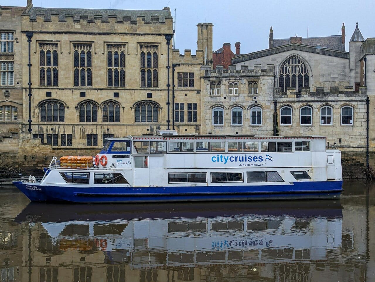 City Cruises boat on the River Ouse in York with historic buildings behind