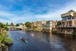 Boats and rowers on the River Ouse in York near a bridge and historic buildings