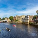 Boats and rowers on the River Ouse in York near a bridge and historic buildings