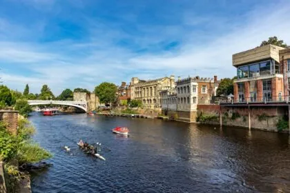 Boats and rowers on the River Ouse in York near a bridge and historic buildings