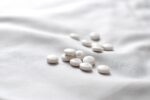 White antihistamine tablets on soft fabric background