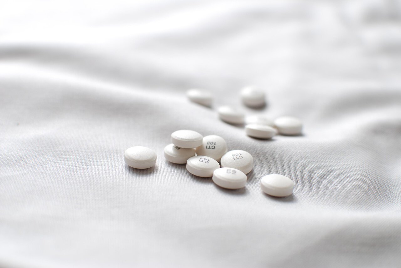 White antihistamine tablets on soft fabric background