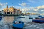 Traditional fishing boats and Bari waterfront marina near Bari Vecchia in Puglia, Italy, under a blue sky.