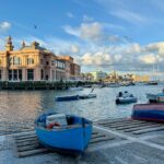 Traditional fishing boats and Bari waterfront marina near Bari Vecchia in Puglia, Italy, under a blue sky.