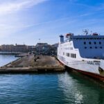 Large passenger ferry docked at Bari Port in Puglia, Italy, with the Adriatic Sea and Bari waterfront in the background.