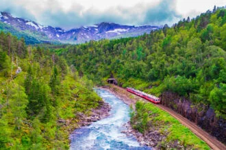 Scenic train travelling through mountains and rivers on the Bergen Line in Norway