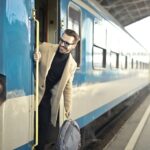 Traveller boarding a blue European night train at Budapest station platform