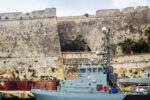 Historic fortress walls of Valletta overlooking naval vessels and harbour infrastructure in Malta