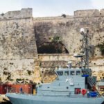 Historic fortress walls of Valletta overlooking naval vessels and harbour infrastructure in Malta