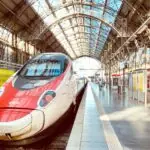 High-speed train at European station platform with modern rail infrastructure and passengers boarding