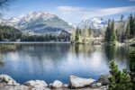 Crystal-clear alpine lake in the High Tatras surrounded by forest and dramatic mountain peaks in Slovakia