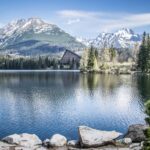 Crystal-clear alpine lake in the High Tatras surrounded by forest and dramatic mountain peaks in Slovakia