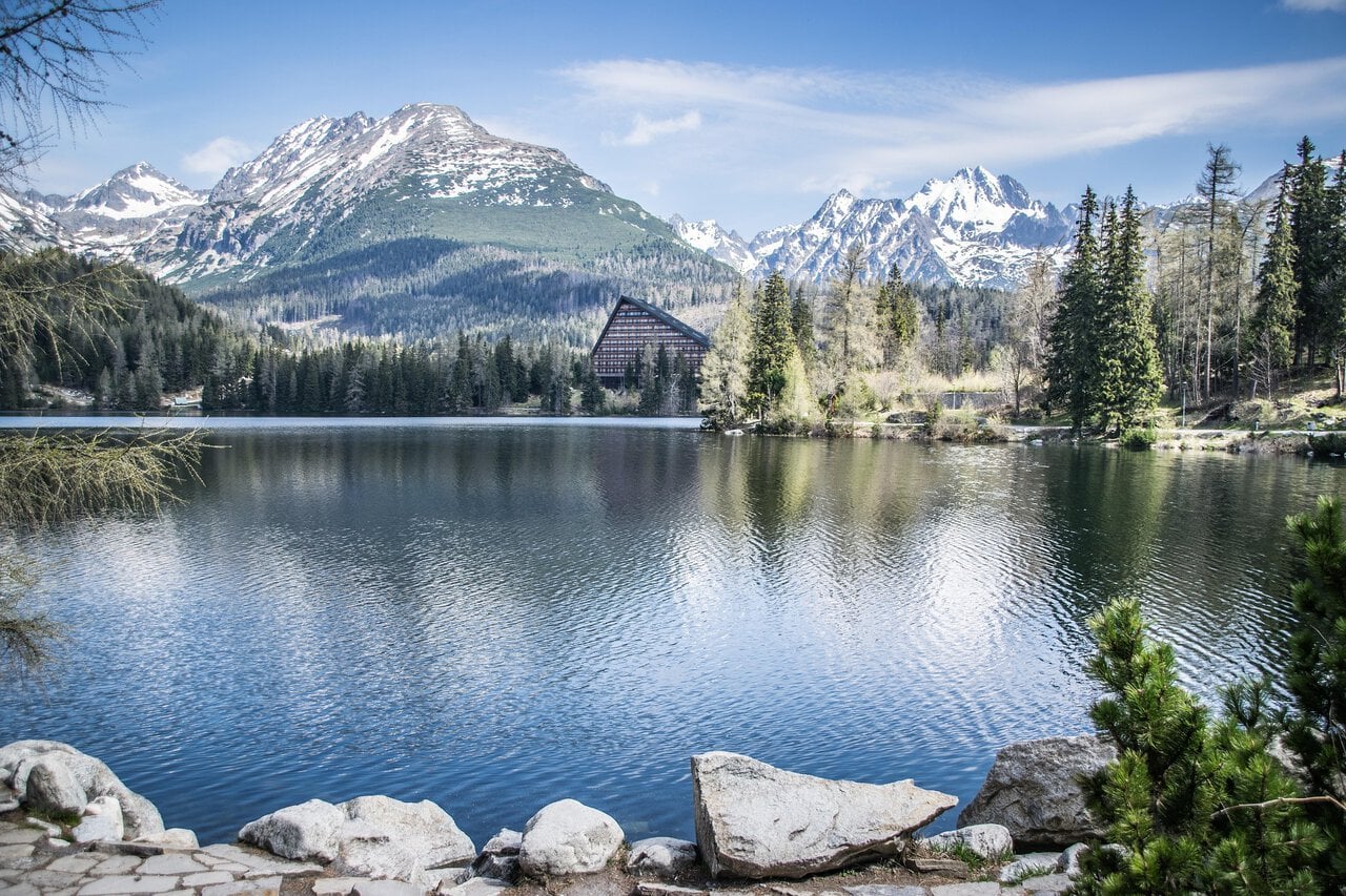 Crystal-clear alpine lake in the High Tatras surrounded by forest and dramatic mountain peaks in Slovakia