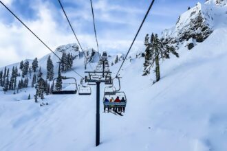 Skiers riding a chairlift through snowy Alpine mountains near Milan ski resorts