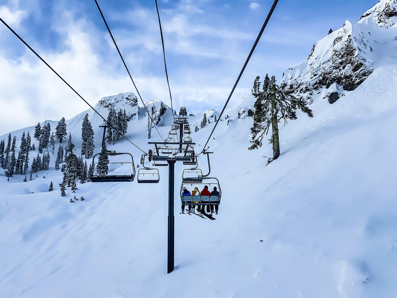 Skiers riding a chairlift through snowy Alpine mountains near Milan ski resorts