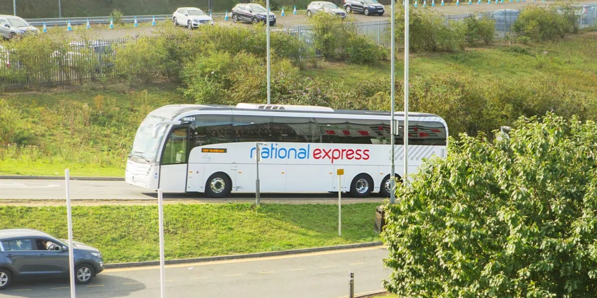 National Express coach travelling on a UK road near a transport hub