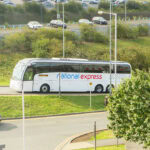 National Express coach travelling on a UK road near a transport hub
