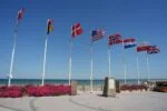 Allied nation flags flying beside a Normandy D-Day memorial overlooking the beaches in northern France