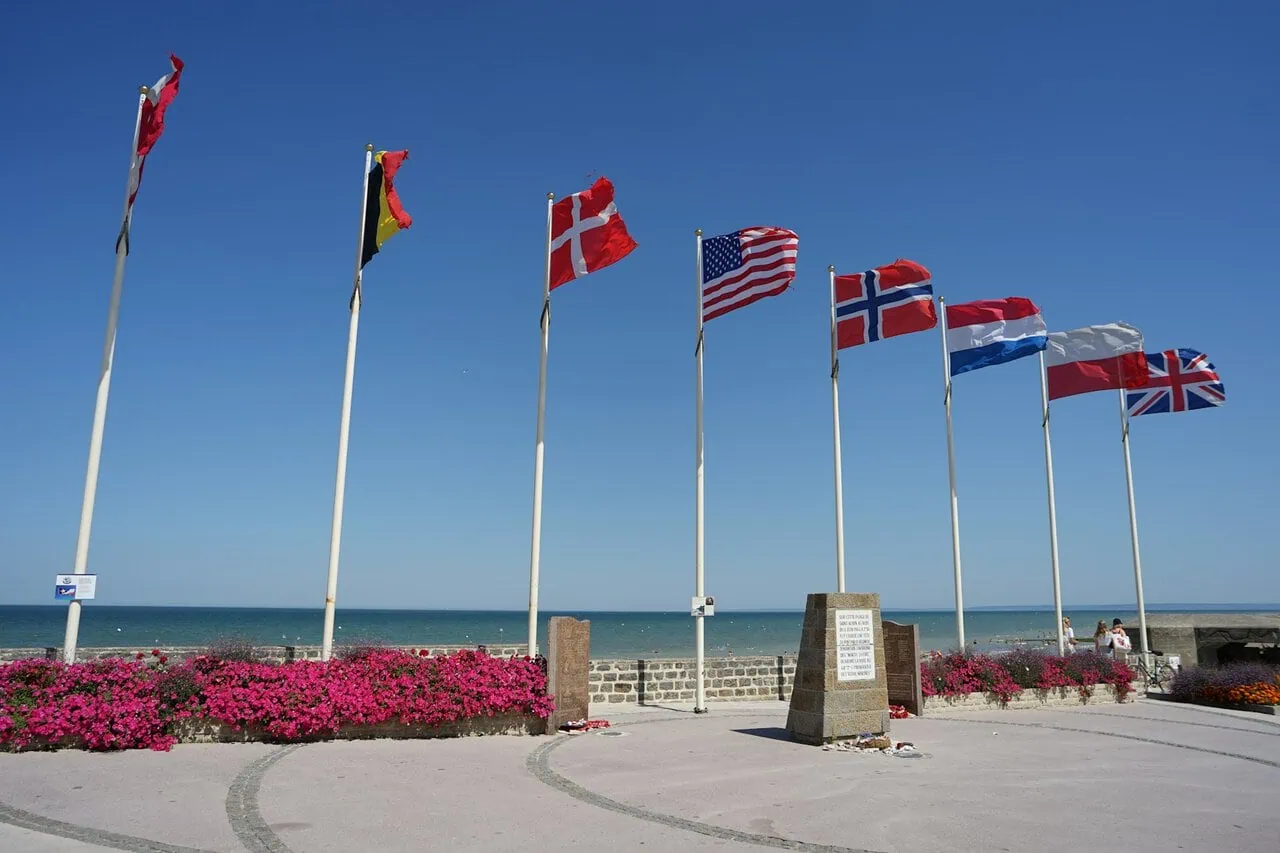 Allied nation flags flying beside a Normandy D-Day memorial overlooking the beaches in northern France