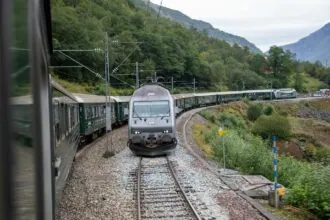 Norwegian overnight train passing through mountain scenery on a scenic rail route in Norway