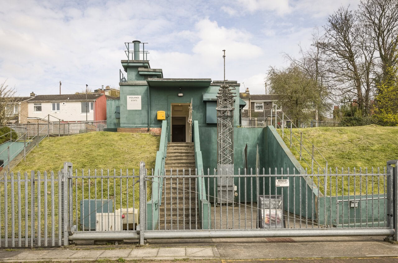 Exterior entrance to a preserved Cold War nuclear bunker in Britain with underground access stairs and security fencing